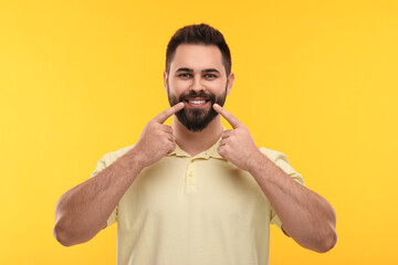 Man showing his clean teeth and smiling on yellow background