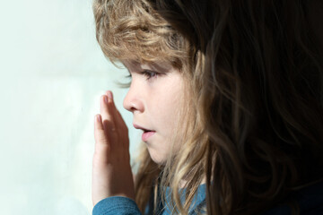 Child dream near window. Kids dreaming face close up. Lifestyle portrait of cute kid. Adorable little blond kid boy sitting near window.