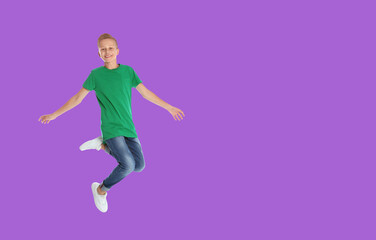 Happy boy jumping on violet background, space for text