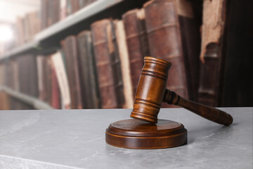 Law. Judge's gavel on light grey marble table near shelves with books indoors, space for text
