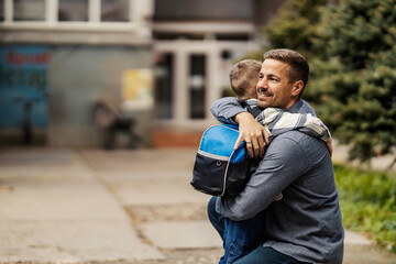 Father and son hugging on kindergarten entrance. - obrazy, fototapety, plakaty