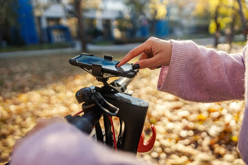Close up of a hand using gps on a phone on an electric scooter outdoors.