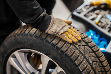 Cropped picture of a vulcanizing worker with car wheel.