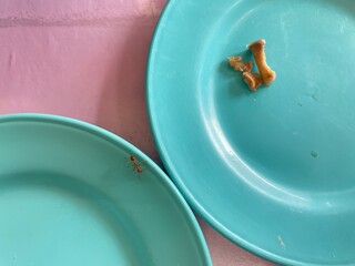 An orange ant is walking on a plate of food.