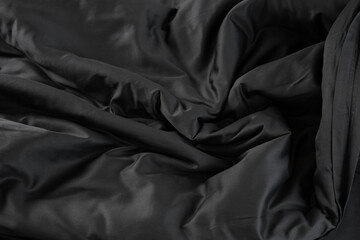 Texture of black satin bed linen with waves fabric