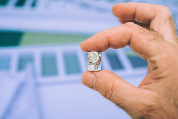 A male hand holds a small metallic part with a hole, essential for assembling furniture. Precision in the making of functional pieces