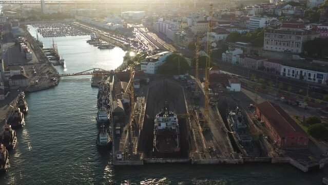 Aerial drone shot of a ship repair dry dock in Lisbon's port, situated on the north bank of the Tagus River. The shipyard is a key facility at the heart of Lisbon harbor.
