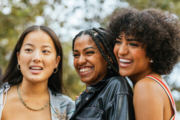 Multiracial women and transgender person smiling taking a selfie outdoors