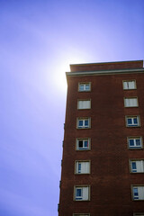 Low angle view of a tall brick house against a blue and violet sky, symbolizing the concept of acid air.