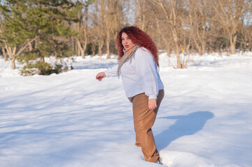 Fototapeta na wymiar A fat red-haired woman in a white sweatshirt walks through snowdrifts. 