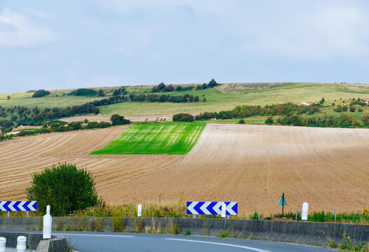 Green oasis of agriculture in the yellow wheat hills, viewed from a French highway, conceptual image for French farming.
