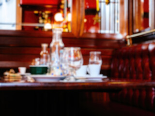 Fototapeta na wymiar A defocused blur view of a cafe pub table with multiple glasses and bottles, capturing the casual and social ambiance of the setting