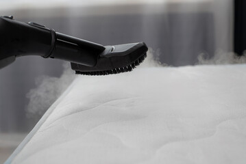 cleaning mattress with professional equipment in bedroom, closeup