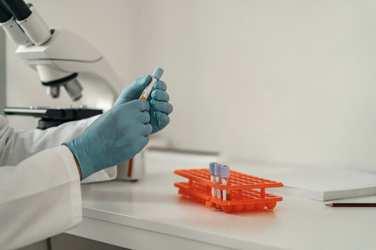 Close up of researcher hand in sterile glove putting test tube into laboratory centrifuge