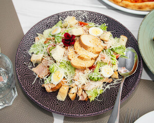 Delicious caesar salad. Caesar salad with cheese, chicken, tomatoes, rusks and green leaves of...