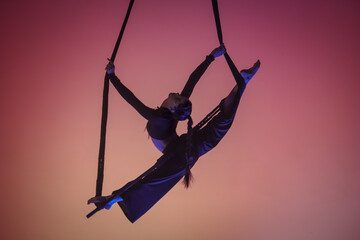 An acrobatic girl demonstrates stretching in twine on an acrobatic trapeze. Acrobatic athlete...