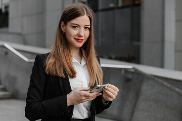 Young business woman wearing black dress code smiling answering message or chatting, using phone...