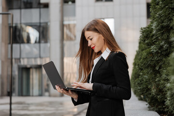 Urban portrait of young business woman works in a laptop outdoor of modern office center background