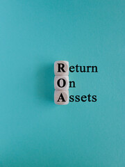ROA- return on assets symbol. Wooden cubes with the inscription return on assets on beautiful blue background. Business concept. Copy space.