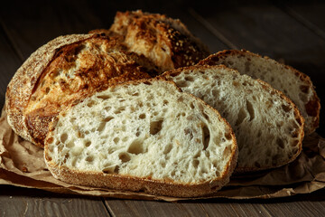 Bread, traditional sourdough bread cut into slices on a rustic wooden background. Concept of traditional leavened bread baking methods. Healthy food.