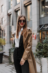 Obraz premium Outdoor portrait of a beautiful young businesswoman in a brown coat at the city
