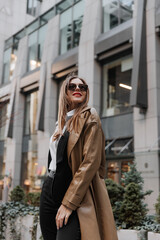 Outdoor portrait of a beautiful young businesswoman in a brown coat at the city