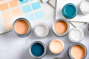 Tiny sample paint cans during house renovation, process of choosing paint for the walls, Peach Fuzz color of the year 2024, color charts on background