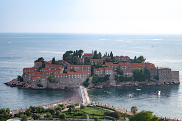 Budva, Montenegro - 06 24 2023: Sveti Stefan beach overlooking a calm blue sea and the island that...