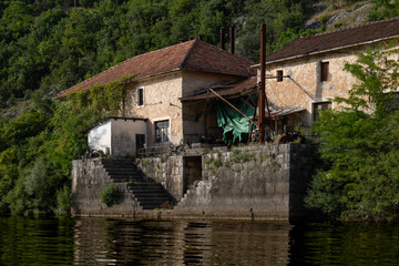 Fototapeta na wymiar Rijeka Crnojevića, Montenegro - 06 24 2023: Local cabin by the Crnojevića river with a great water view, surrounded by lush green mountains