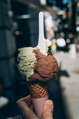 Tasty gelato in waffle cone, pistachio and triple chocolate ice cream scoops. Amazing treat during hot summer in town