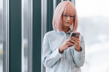 Woman with pink hair is in the office. Young worker