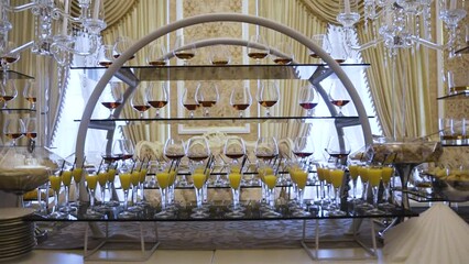 A luxurious dessert bar with layered racks of orange and brown beverages, elegant glassware against a sumptuous room backdrop, showcasing a sophisticated event catering setup with a variety of sweet