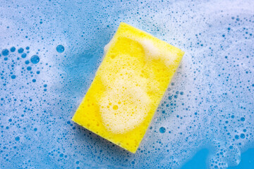 Cleaning sponge in foam of dishwashing liquid. Washing dishes concept