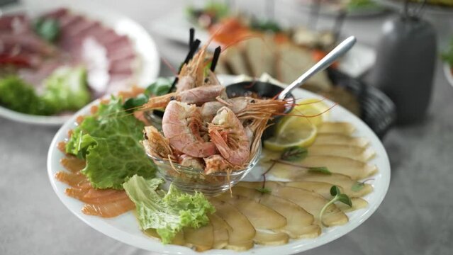 A seafood platter featuring sliced smoked fish, fresh prawns, lemon slices, and lettuce, served with a side of cocktail sauce, presented on a white plate for a gourmet dining experience.