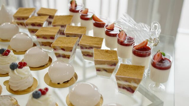 decadent dessert spread with a variety of treats including a large platter of white marshmallows, cupcakes with blueberry and red currant toppings, and glossy iced pastries.
