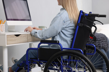 Obraz premium Woman in wheelchair using computer at home, closeup