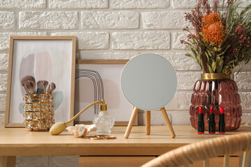 Mirror, jewelry, makeup products and perfume on wooden dressing table in room