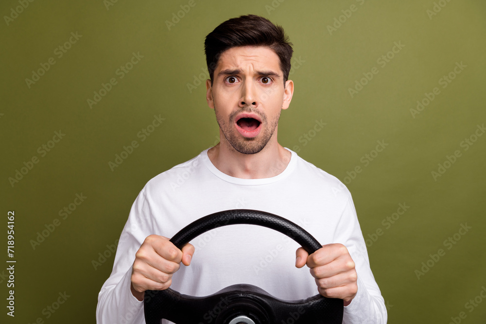 Canvas Prints Photo of young surprised man holding steering wheel crazy riding automobile with manual gearbox isolated on khaki color background