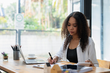 Black businesswoman sitting in front of laptop in office, Check operating results documents and...