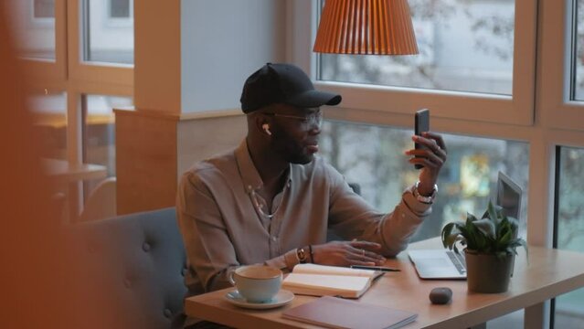An African-American man makes a video call using a smartphone. He says no, and shows with his hands that he is against it. He speaks confidently and waves his hands.