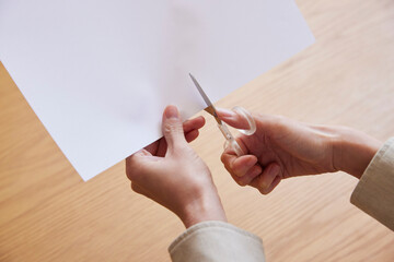 ハサミで紙を切る女性の手元