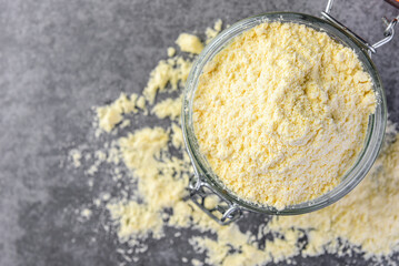 Corn flour in glass jar on gray background.