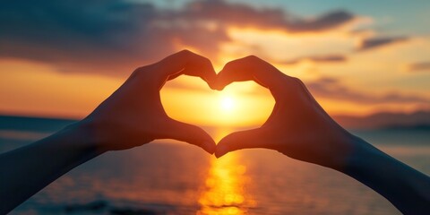 A close-up of hands forming a heart shape with a beautiful sunset in the background - love and togetherness concept Ideal for romantic themes and greeting cards - obrazy, fototapety, plakaty