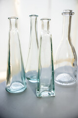 Collection of decorative transparent glass vases on a gray background.  Backlit against a light...