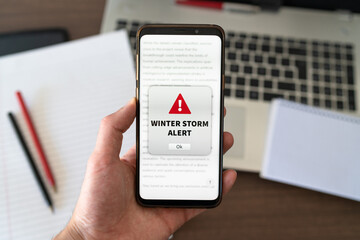 Winter storm alert notification appearing on the phone while in use. Bad weather concept.