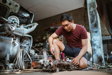 mechanic cleans the cylinder coupling when dismounting the engine using a duster gun