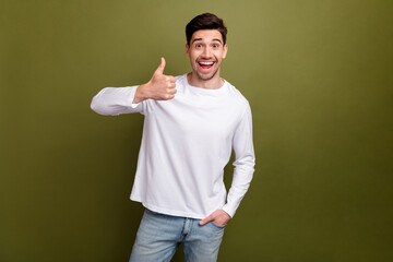 Portrait of astonished positive man arm finger demonstrate thumb up isolated on khaki color...