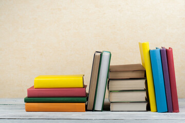 Book stacking. Open book, hardback books on wooden table and blue background. Back to school. Copy space for text.