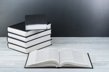 Open books on wooden table, black board background. Back to school. Education business concept.