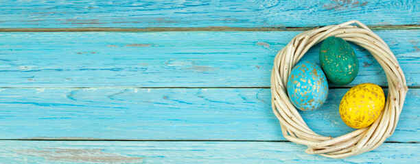 Happy Easter.Colorful shiny eggs on wooden table background. wreath woven from the vines. Copy space for text. Top view. Banner